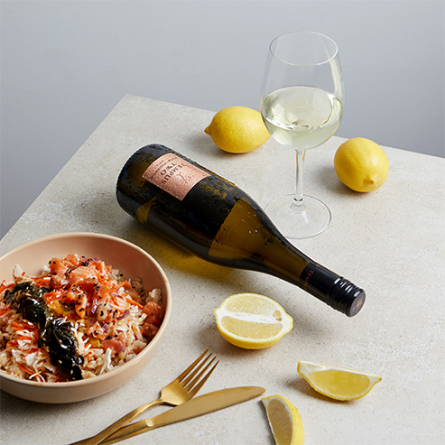 Bottle and glass of Tempus Two Copper range varietal with a rice dish and lemon
